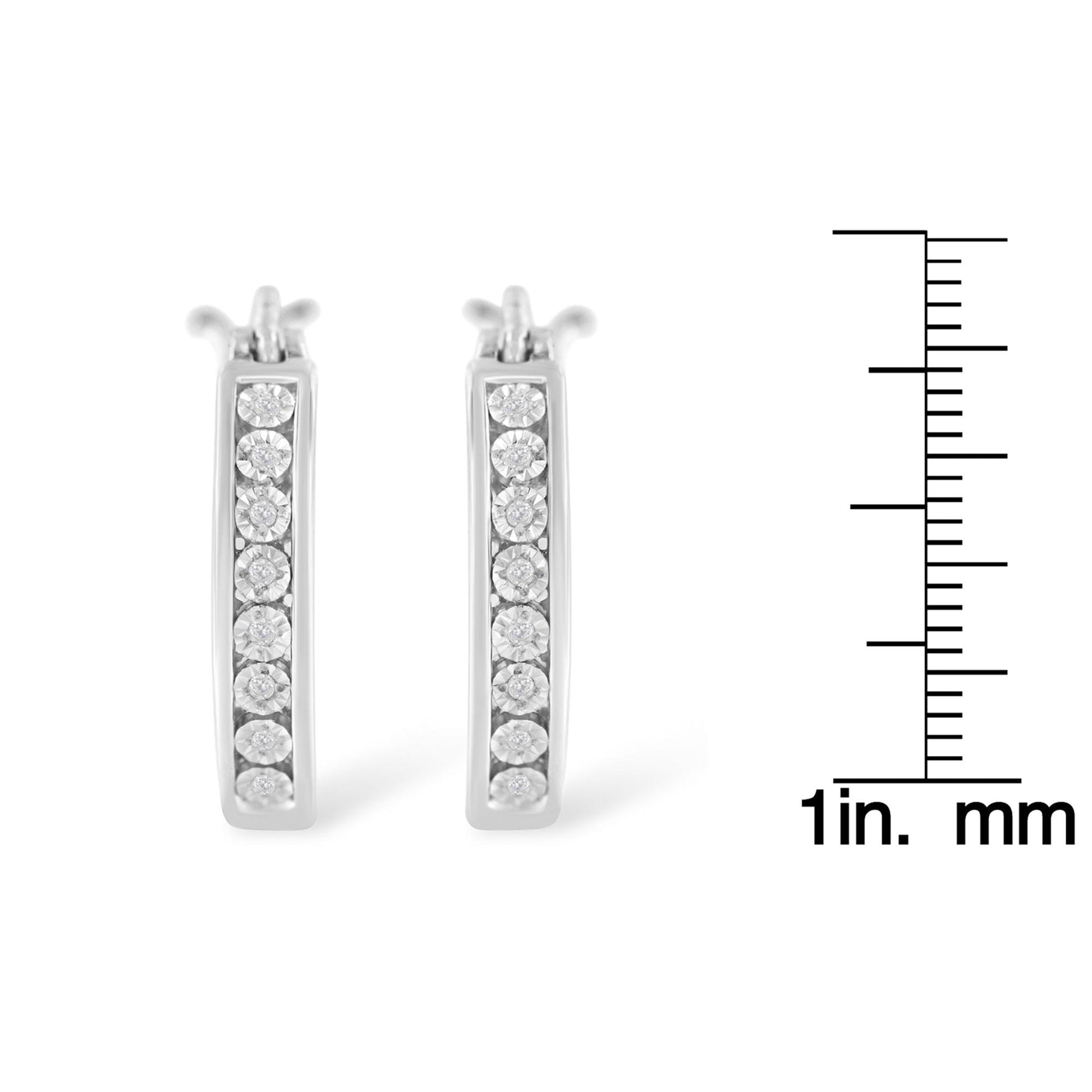 Front view of pair of white metal earrings with white round gemstones set in a vertical line, displayed next to a ruler for size reference.