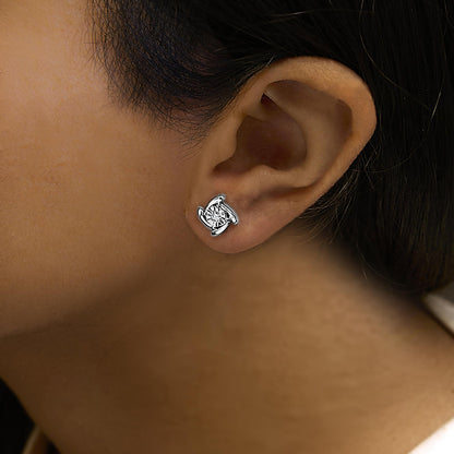 Close-up side angle of a white metal earring with a round white gemstone in a miracle setting, worn on a model.