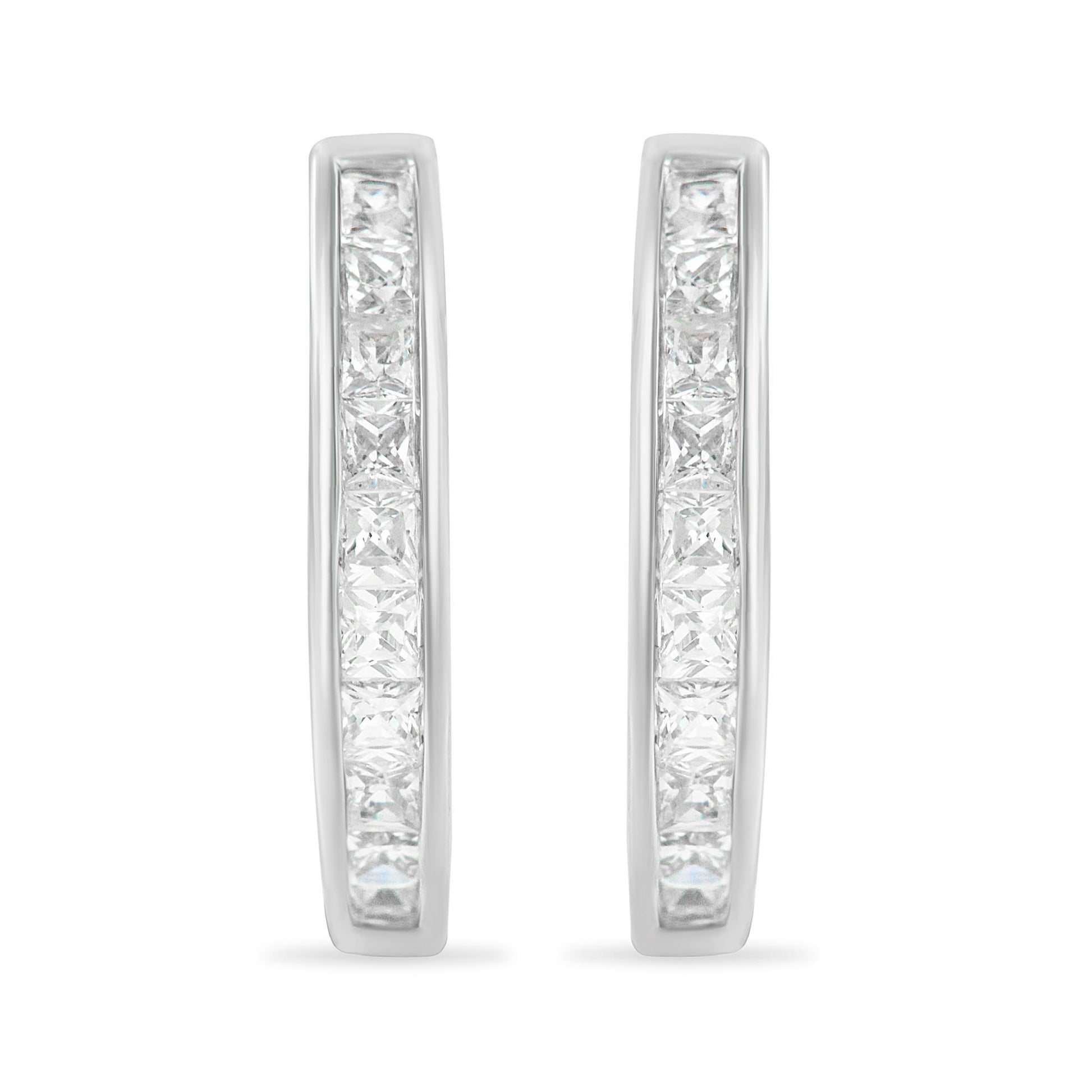 Front-facing view of white metal hoop earrings set with two rows of princess-shaped white channel-set gemstones.