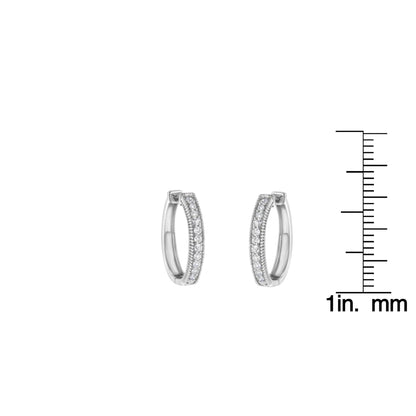 Front-facing shot of white metal hoop earrings with rows of white round gemstones in prong settings, shown next to a ruler for size reference.