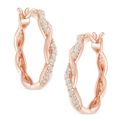 Close-up front angle of a pair of rose-colored hoop earrings with a twisted design and white round gemstones in pave setting.