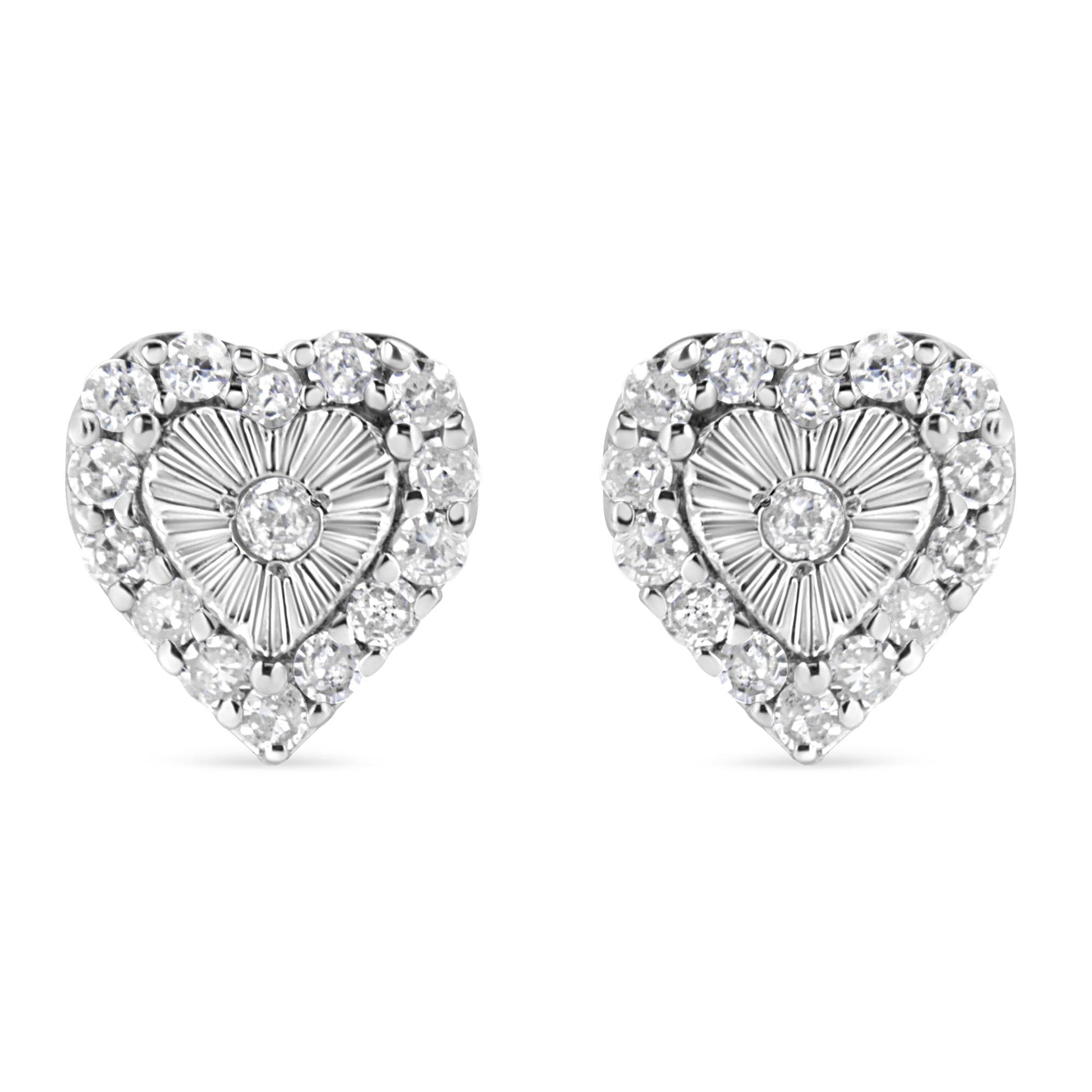 Front-facing view of a pair of white metal heart-shaped earrings with a central round white gemstone in miracle setting, surrounded by multiple round white gemstones in prong setting.