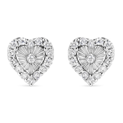 Front-facing view of a pair of white metal heart-shaped earrings with a central round white gemstone in miracle setting, surrounded by multiple round white gemstones in prong setting.