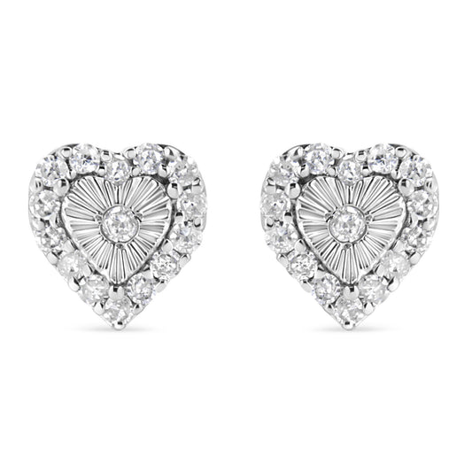 Front-facing view of a pair of white metal heart-shaped earrings with a central round white gemstone in miracle setting, surrounded by multiple round white gemstones in prong setting.