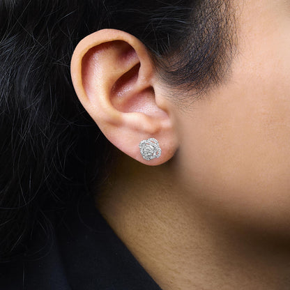 Close-up side view of a white metal earring with round white gemstones in prong settings, worn on a model's ear.