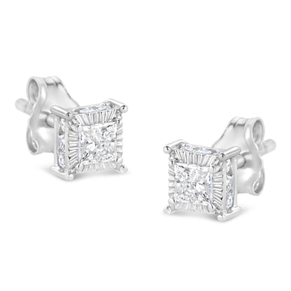 Pair of white metal stud earrings with princess shape white gemstones in the center surrounded by smaller round white gemstones on all sides, shown from an angled front view.