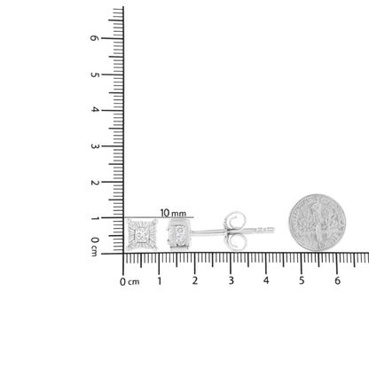 Side view of white metal stud earrings with princess-shaped white gemstones in prong settings and round white gemstones in channel settings, displayed on a ruler for size reference with a coin nearby.