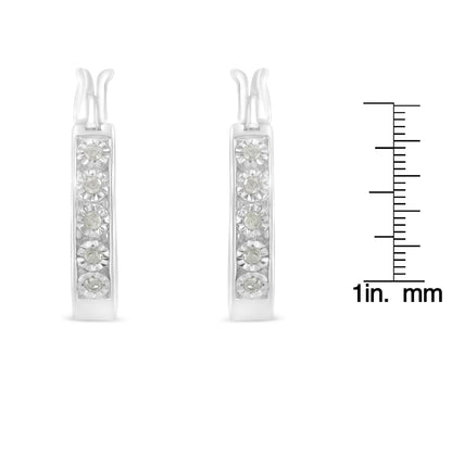 Front view of white metal earrings with five round white gemstones in miracle settings, shown next to a ruler for size reference.