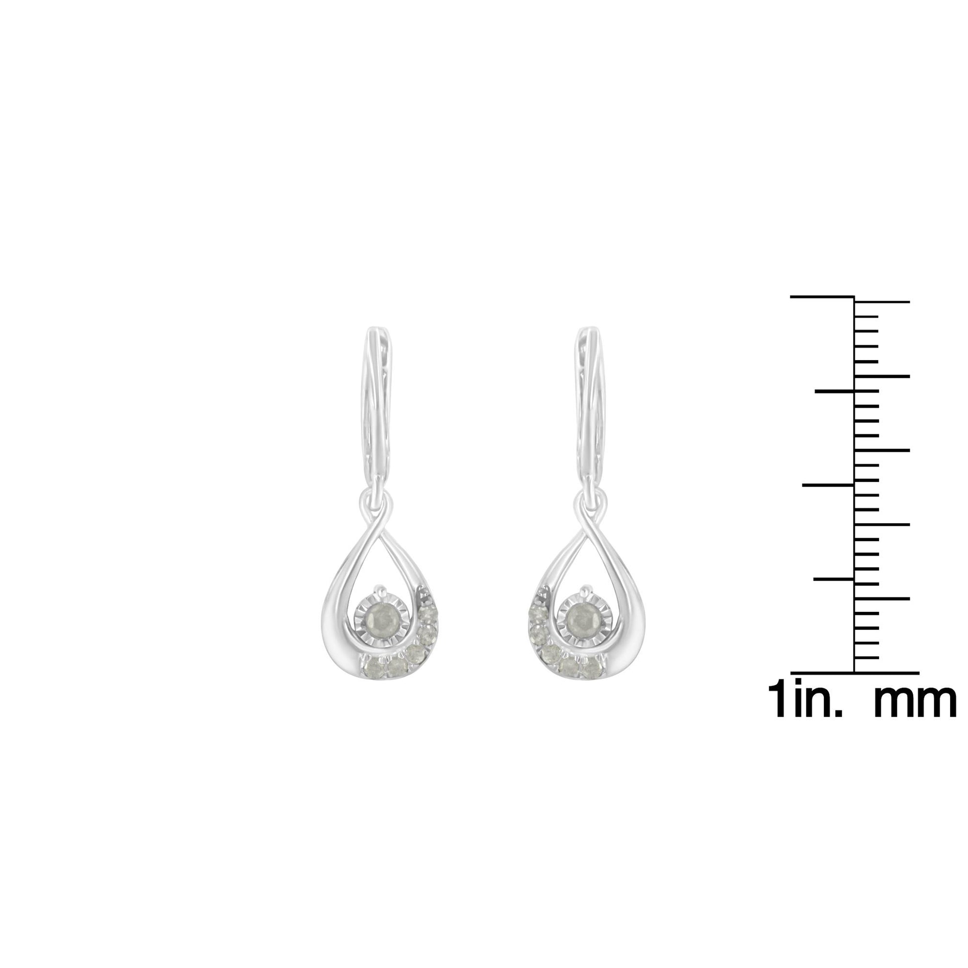 Pair of white metal drop earrings with round white gemstones in pave setting, front view on a ruler for size reference.