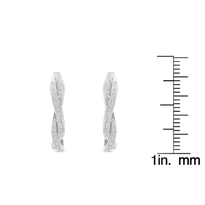Front view of white metal earrings with two intertwined rows of white round prong-set and white baguette channel-set gemstones, shown next to a ruler for size reference.
