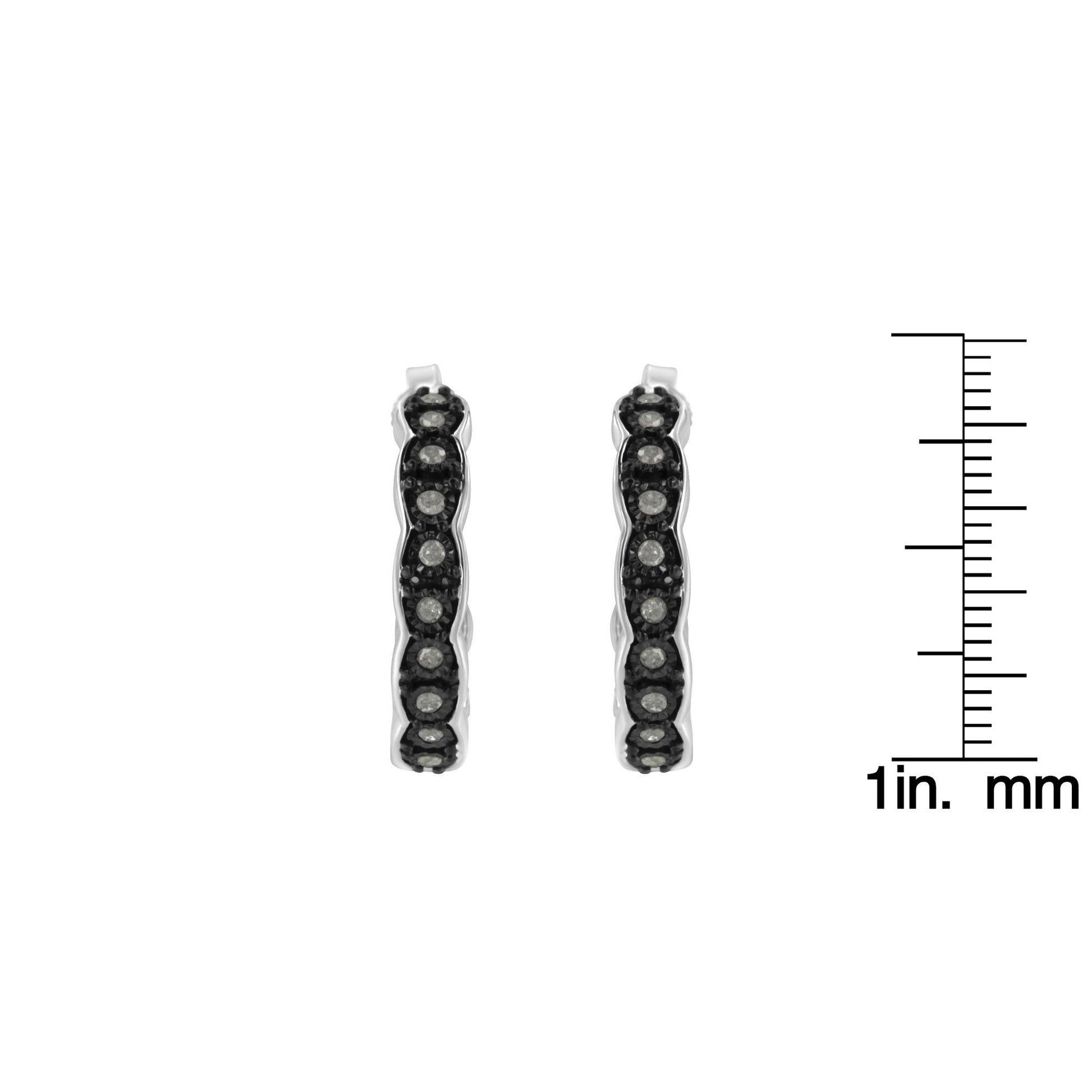 Front view of two-toned hoop earrings with round white gemstones in miracle setting, shown next to a ruler for size reference.