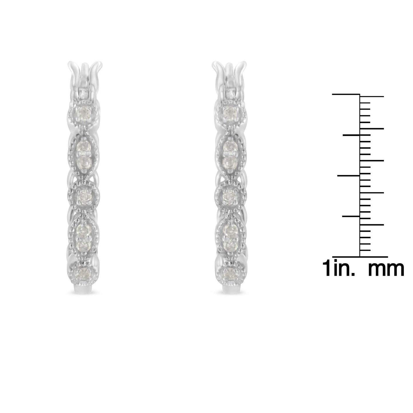 Front view of a pair of white metal earrings encrusted with round white gemstones in prong settings, displayed next to a ruler for size reference.
