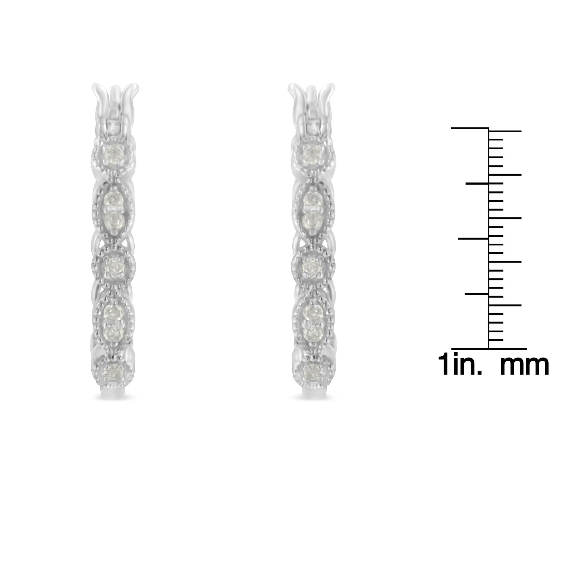 Front view of a pair of white metal earrings encrusted with round white gemstones in prong settings, displayed next to a ruler for size reference.