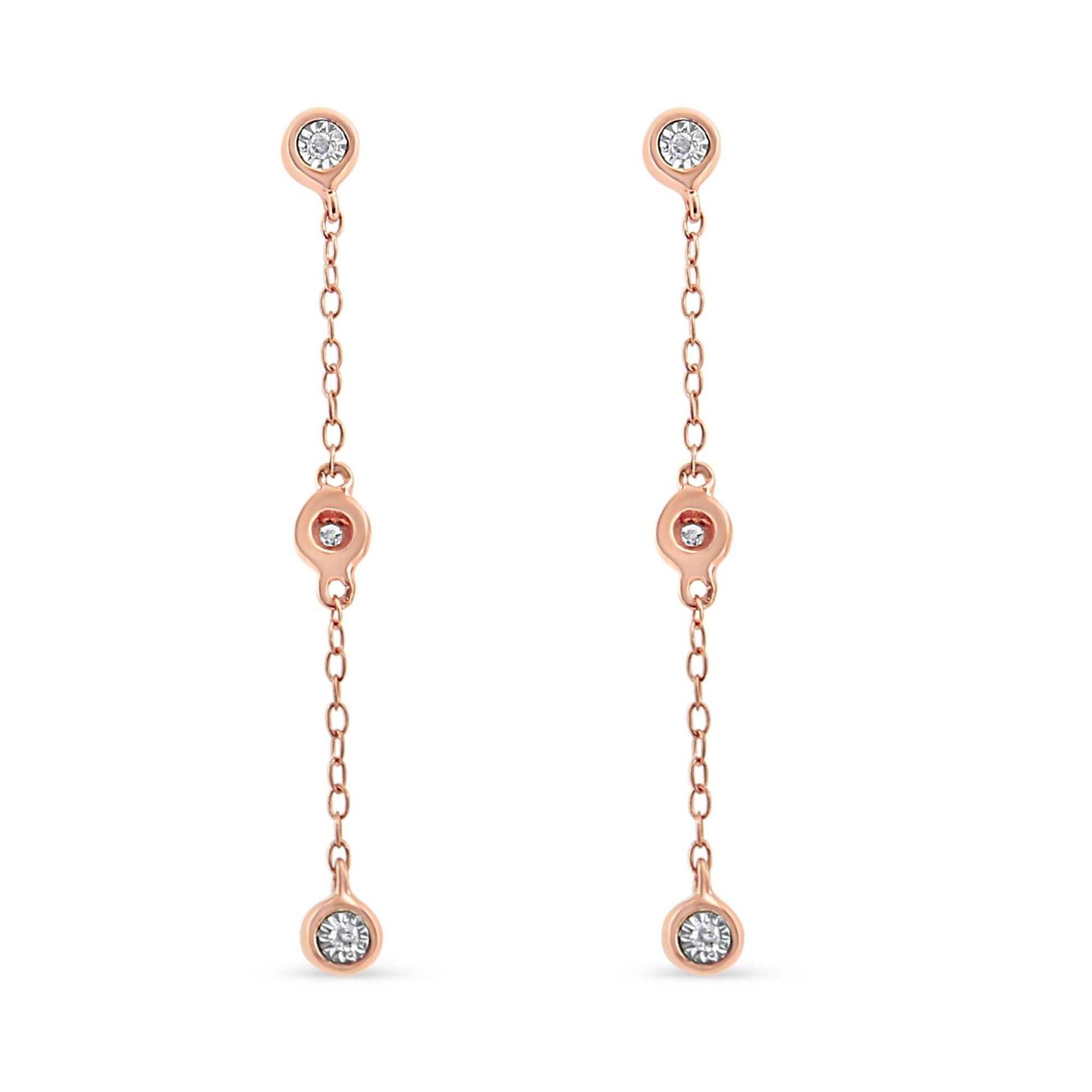Front view of a pair of rose metal dangle earrings with three white gemstones in a miracle setting along each chain.