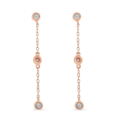 Front view of a pair of rose metal dangle earrings with three white gemstones in a miracle setting along each chain.