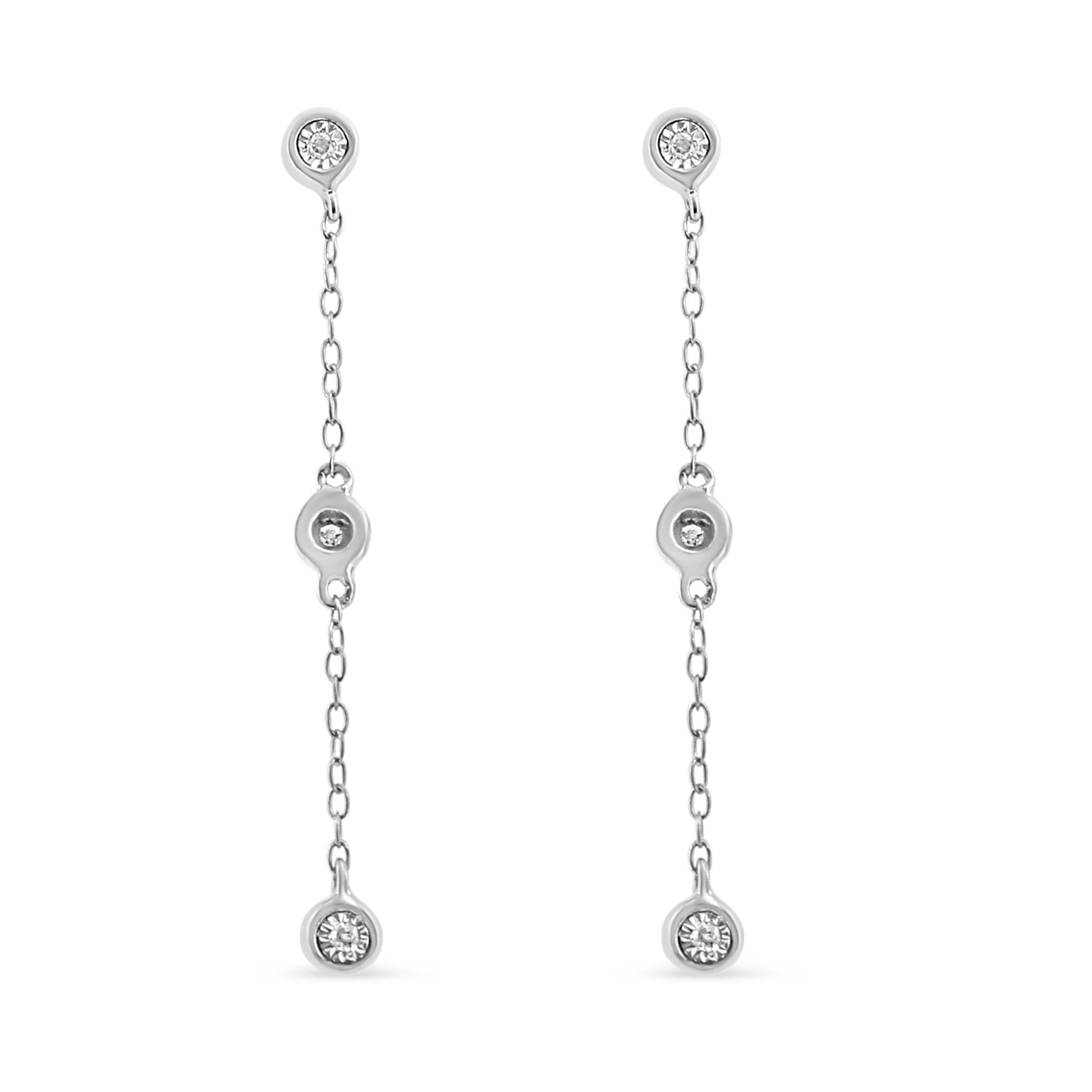 Front view of white metal drop earrings with three round white gemstones each set along a slender chain.