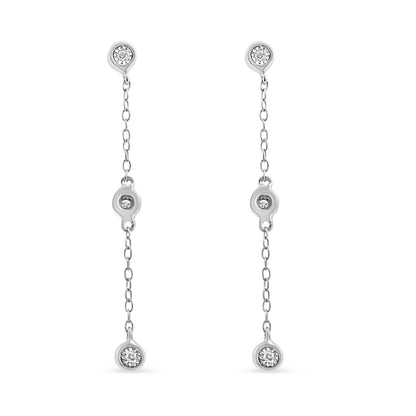 Front view of white metal drop earrings with three round white gemstones each set along a slender chain.