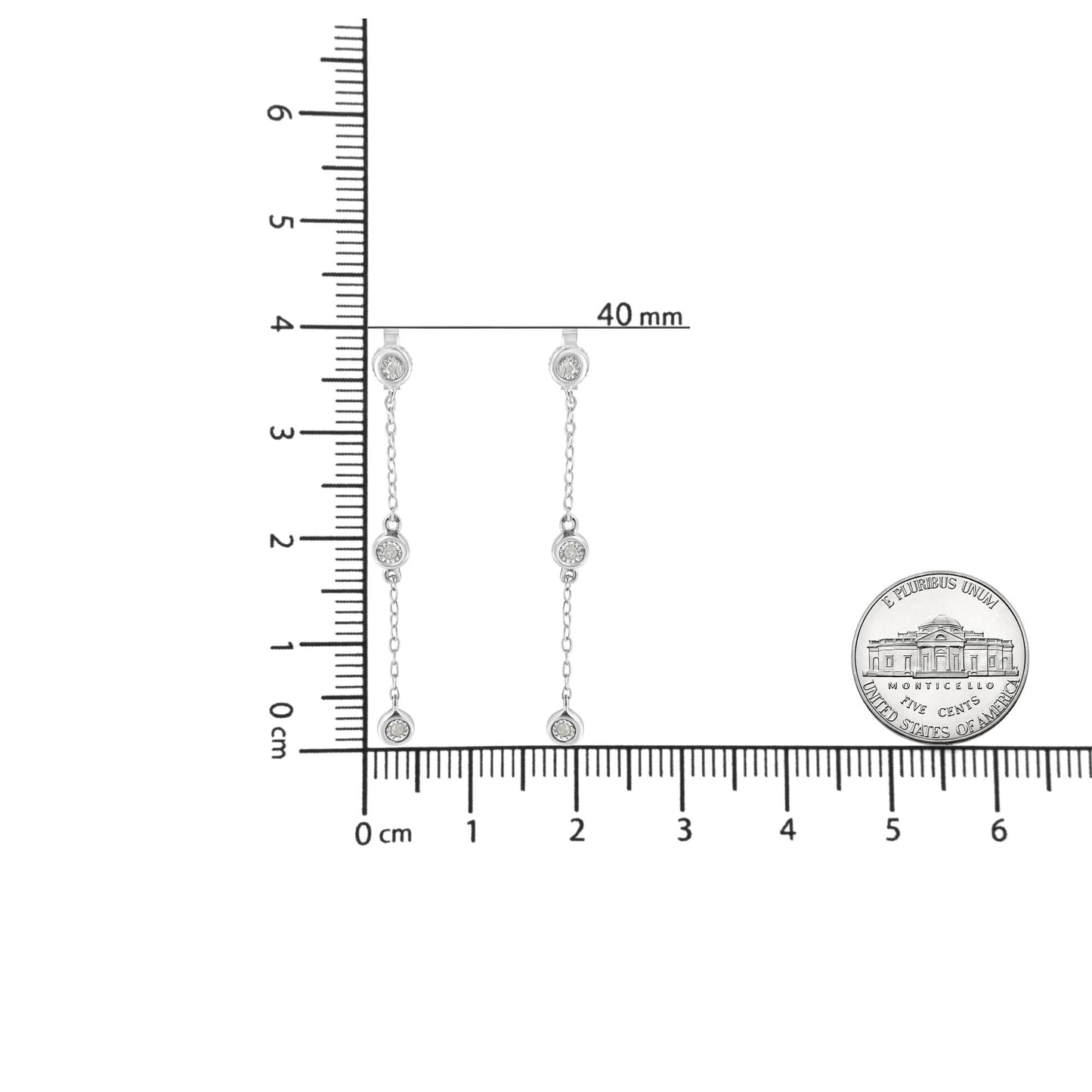 Front view of white metal drop earrings with three round white gemstones in miracle settings connected by thin chains, displayed on a ruler and next to a coin for size reference.