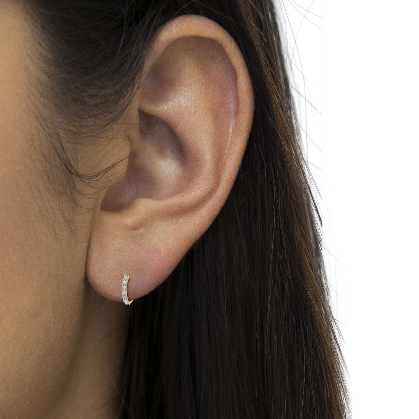 Close-up side view of a two-toned small hoop earring with a row of white round gemstones in miracle setting, worn on a model.