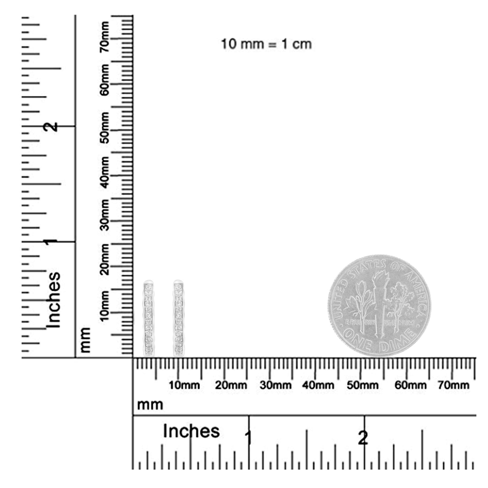 Close-up front angle of white metal earrings with round white gemstones in pave setting, shown on a ruler and a coin for size reference.