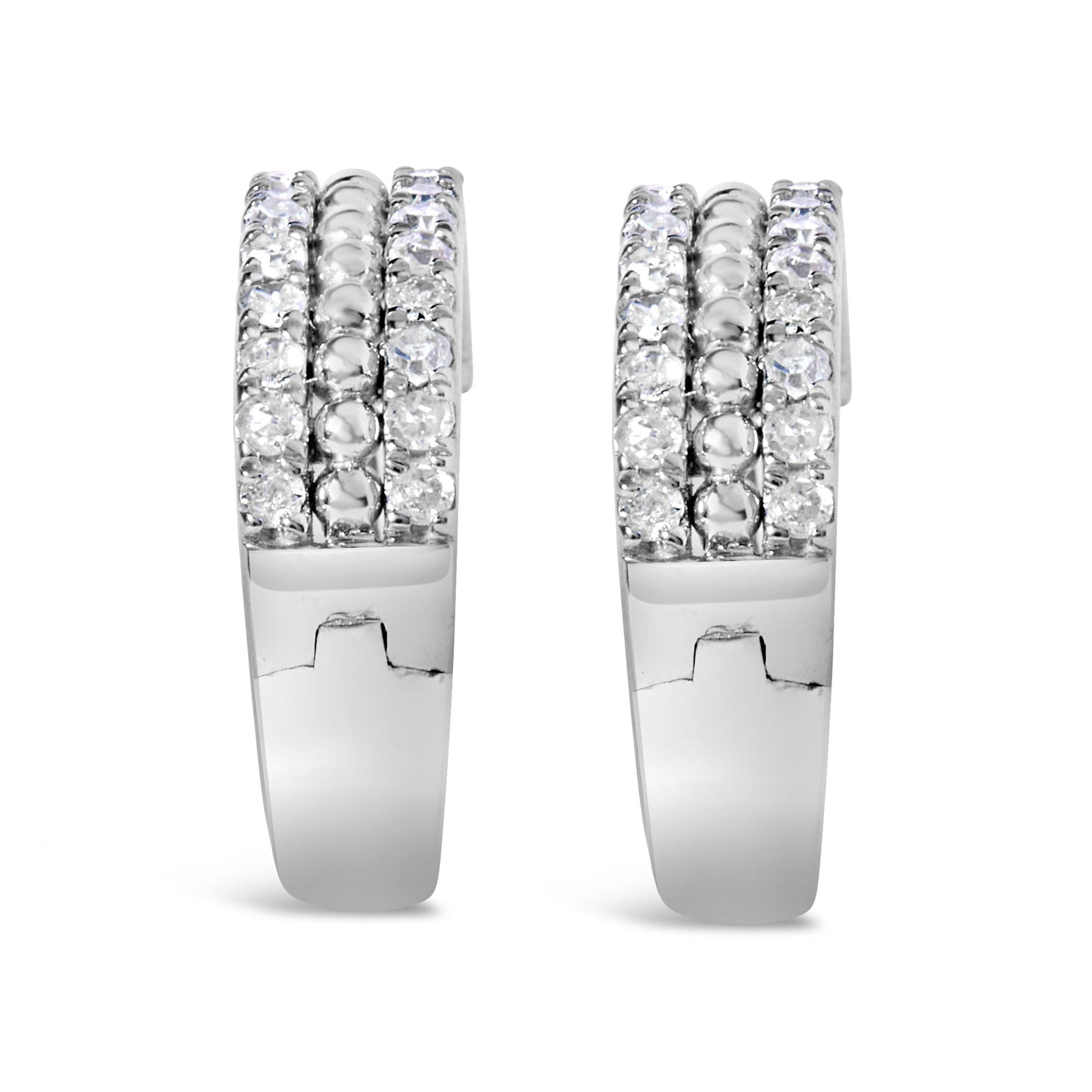 Front view of a pair of white metal hoop earrings with three rows of round white gemstones in a pave setting along the front.