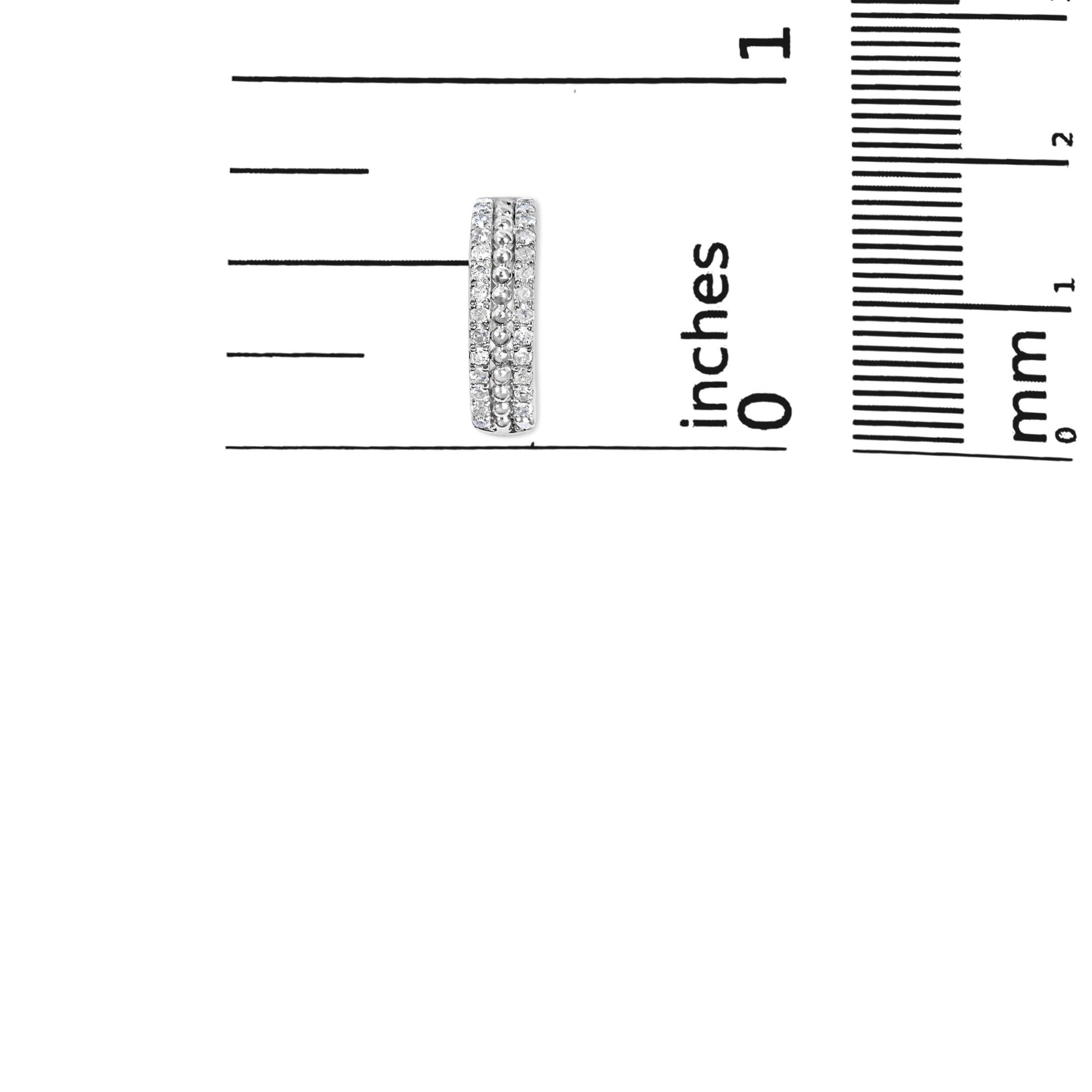 Close-up front view of a white metal earring with three vertical rows of round white gemstones in pave setting shown on a ruler for size reference.