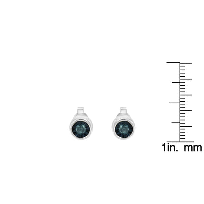 Front-facing shot of white metal round stud earrings featuring blue gemstones in a miracle setting, shown next to a ruler for size reference.