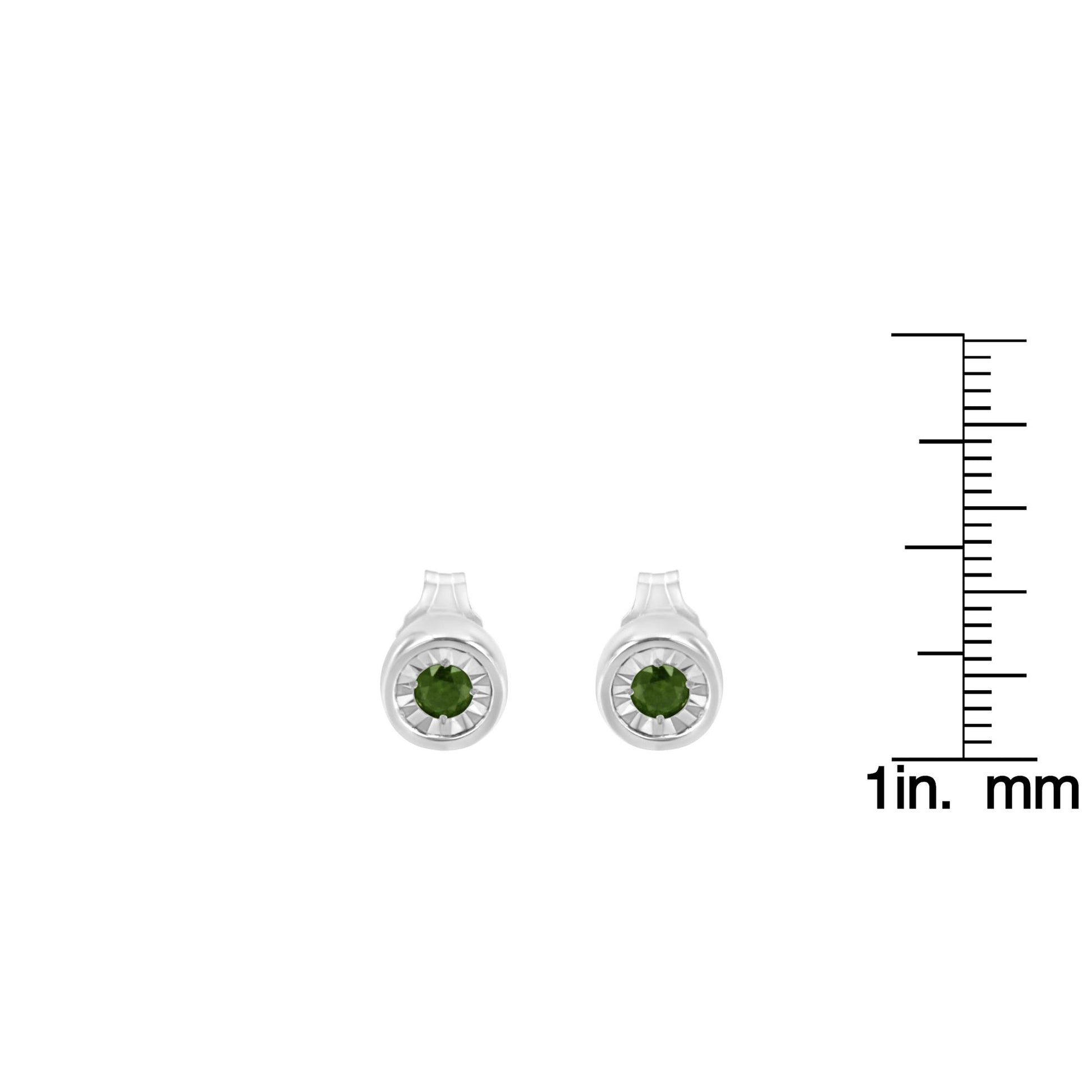 Front view of white metal round stud earrings with green gemstones in miracle settings, shown next to a ruler for size reference.