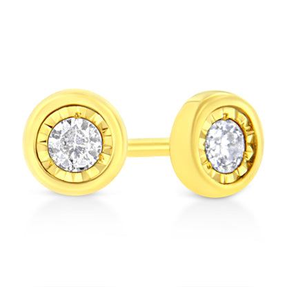 Close-up front angle of yellow metal stud earrings each featuring a round white gemstone set in a miracle setting.