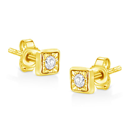 Pair of yellow metal stud earrings with square settings and round white gemstones in the center, angled view.