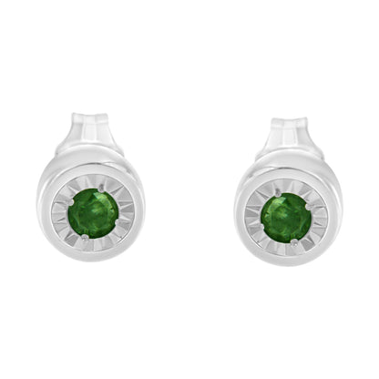 Front-facing shot of white metal round earrings featuring a central green gemstone in a miracle setting.