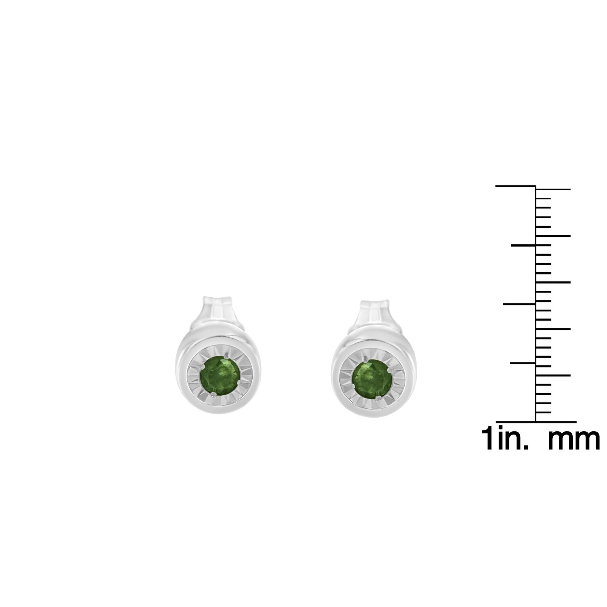 Front view of white metal stud earrings featuring round green gemstones in a miracle setting, displayed next to a ruler for size reference.