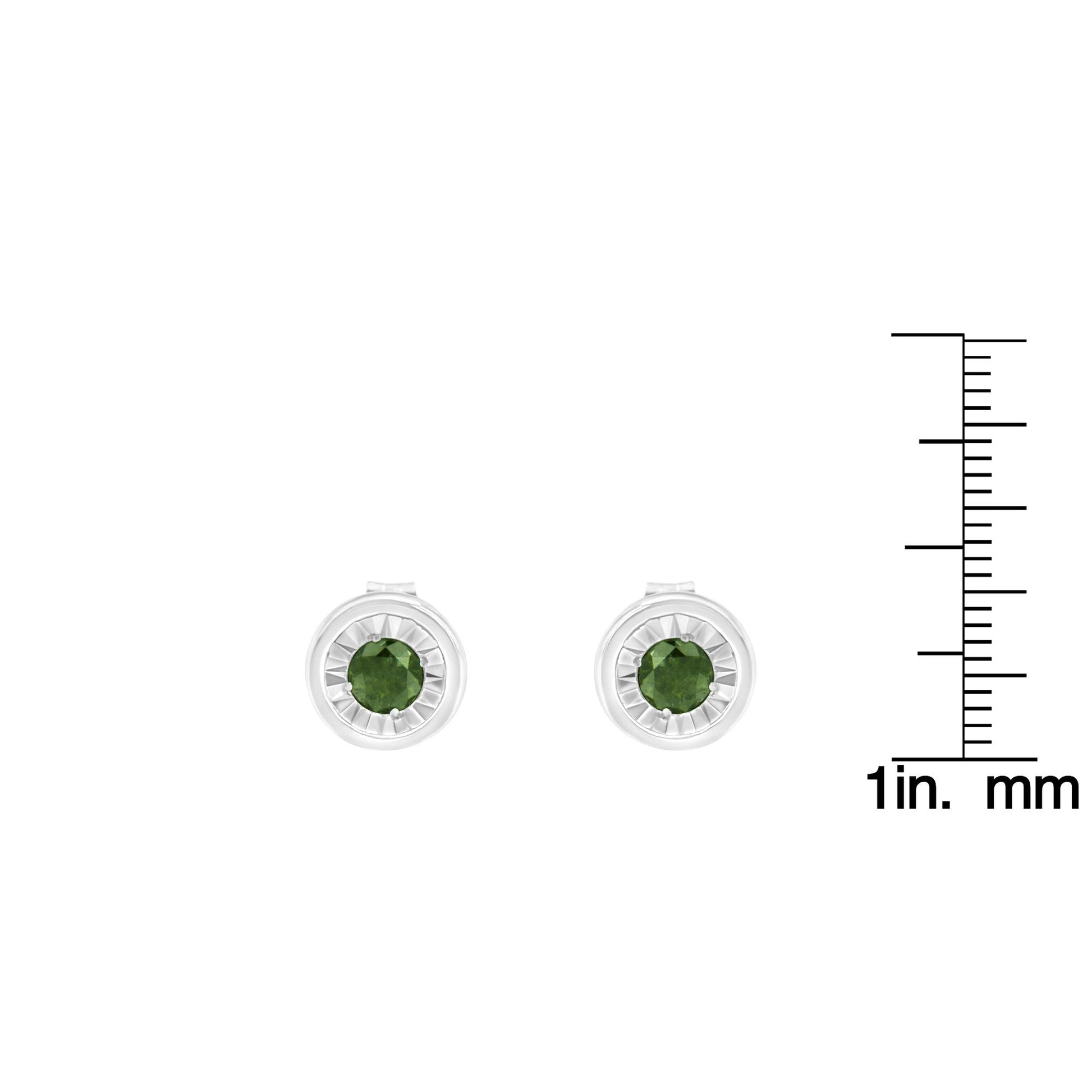 Front angle view of white metal stud earrings with round green gemstones in miracle settings, shown next to a ruler for size reference.