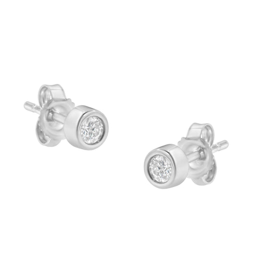 Pair of white metal stud earrings with round white gemstones in bezel settings, shown at a slight angle.