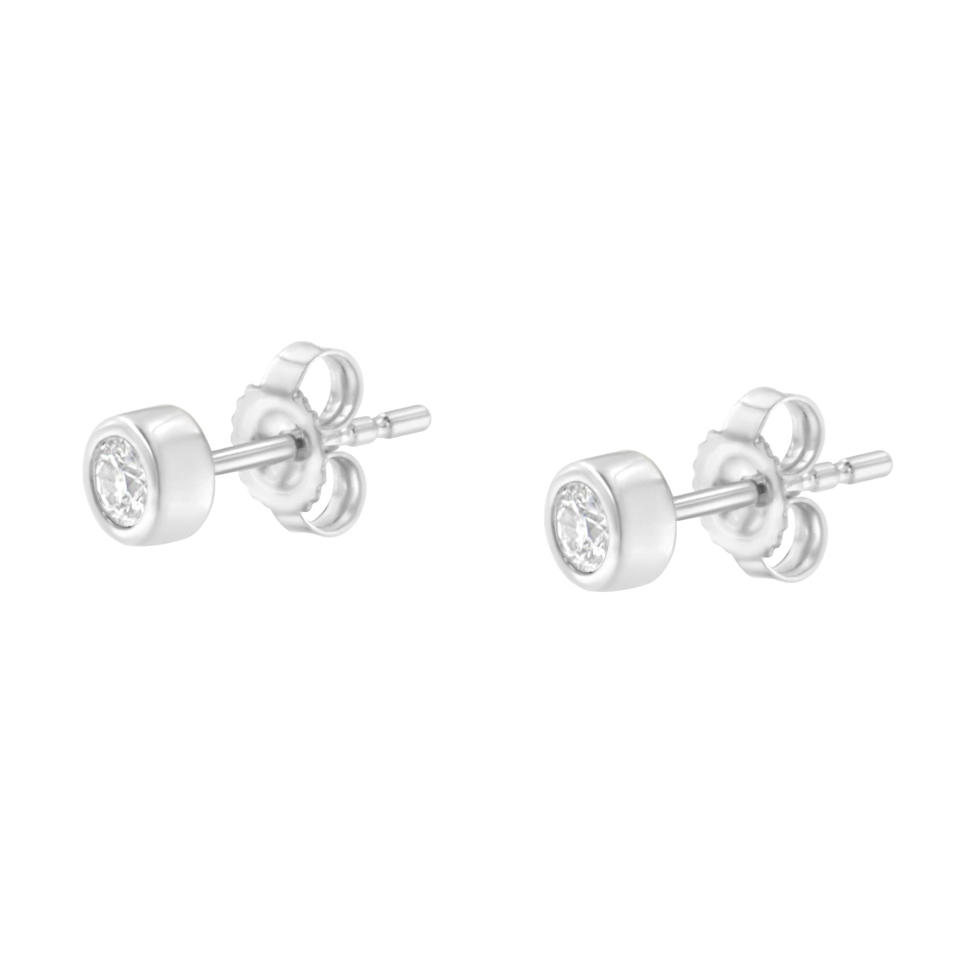 Pair of white metal stud earrings with round white gemstones in bezel settings, displayed at a slightly angled side view.