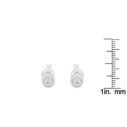 Front view of white metal stud earrings with round white gemstones in bezel settings, shown next to a ruler for size reference.
