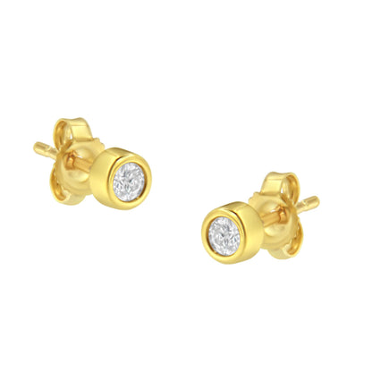 Pair of yellow metal stud earrings with round white gemstones in bezel setting, viewed from a slightly angled front.