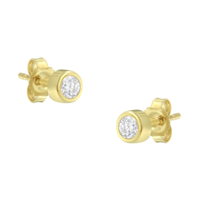 Close-up front-angle shot of yellow metal stud earrings with round white gemstones in bezel settings.