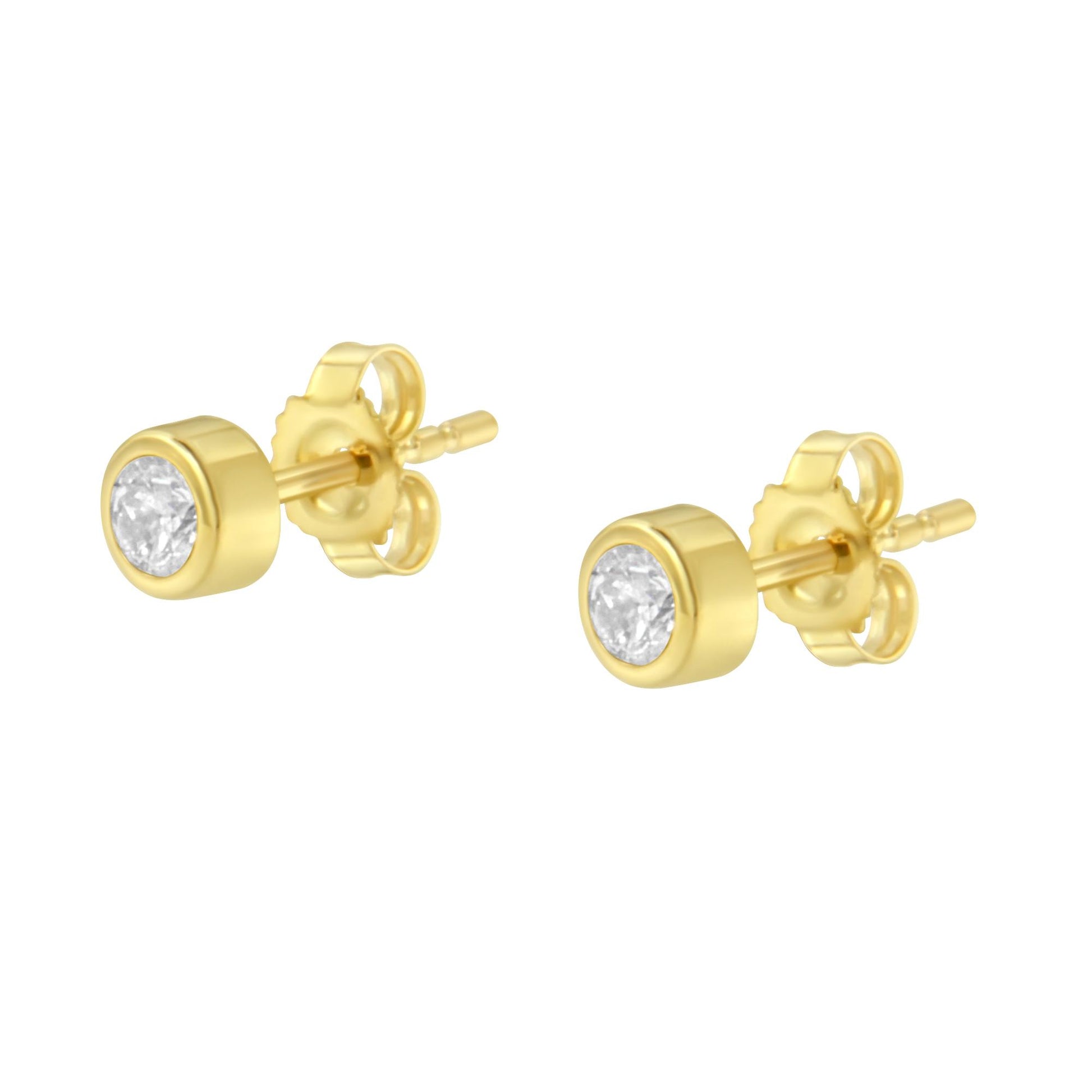Pair of yellow metal stud earrings with round white gemstones in bezel settings, shown at a slight angle.