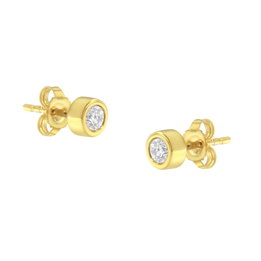 Pair of yellow metal stud earrings with round white gemstones in bezel settings, shown from a slightly angled front view.