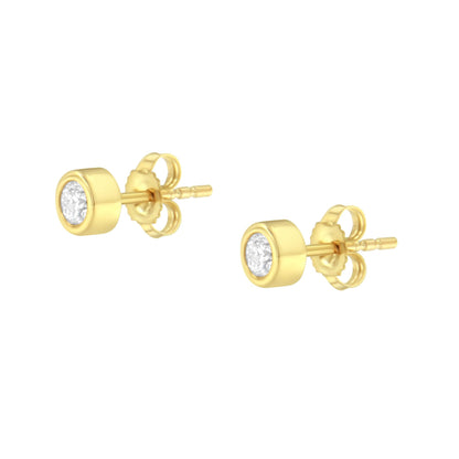 Pair of yellow metal stud earrings with round white gemstones in bezel settings, shown at a slight angle.
