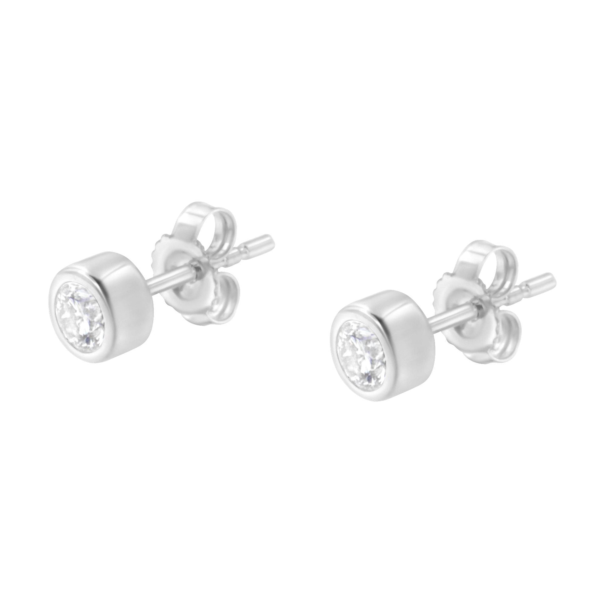 Pair of white metal stud earrings with round white gemstones in bezel settings, shown from a side angle.