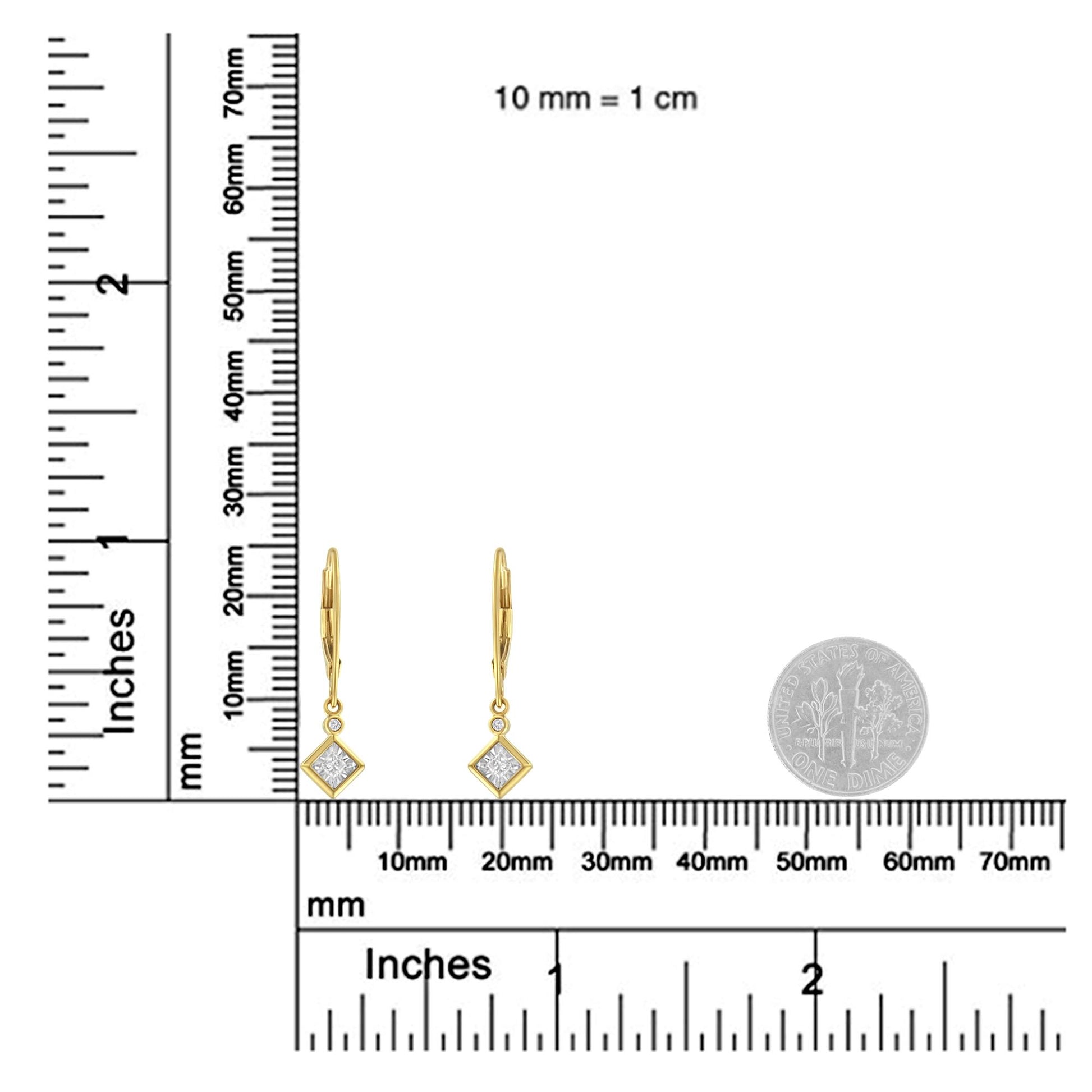 Pair of yellow and white metal drop earrings with square and round white gemstones, shown on a ruler and next to a coin for size reference, front-facing angle.