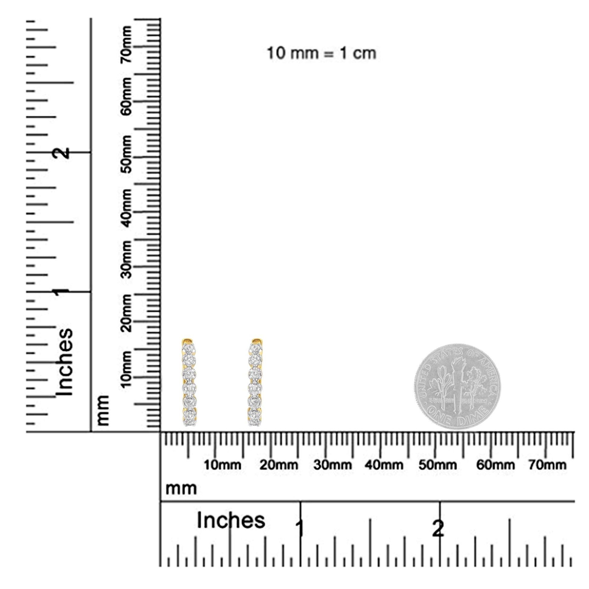 Pair of yellow metal earrings with vertical rows of prong-set round white gemstones, shown from the front on a ruler and next to a coin for size reference.