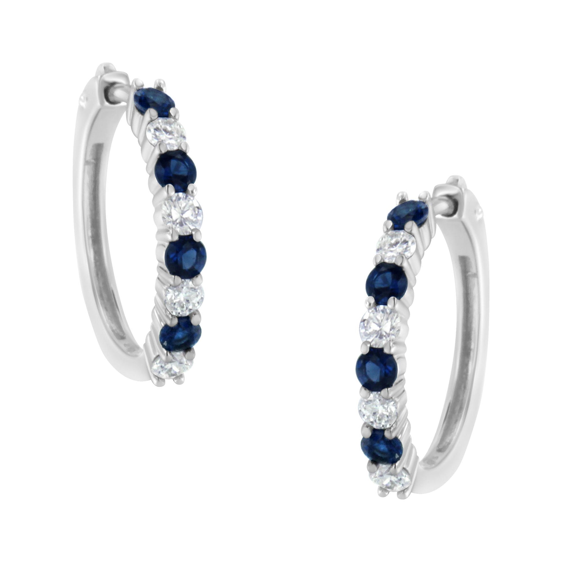 Pair of white metal hoop earrings with alternating round white and blue gemstones in prong settings, shown at a slight angle.