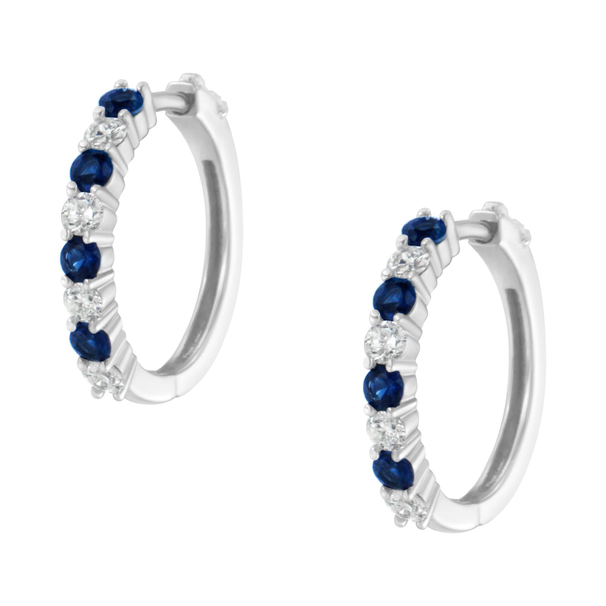 Pair of white metal hoop earrings with alternating round white and blue gemstones in prong settings, shown at a slight angle.