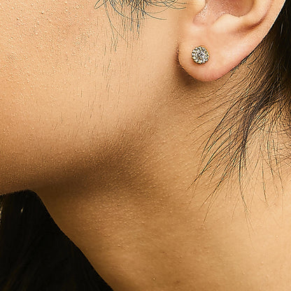 Close-up side view of a yellow metal round stud earring with white gemstones worn on a model's ear.