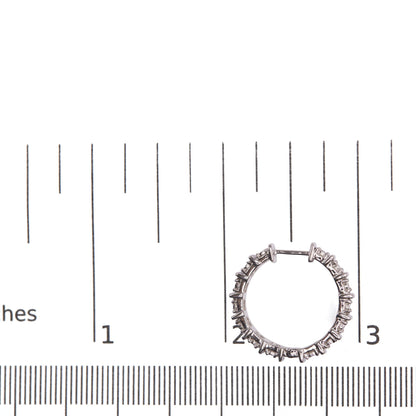 White metal hoop earring with round white gemstones in miracle setting, photographed flat on a ruler for size reference.