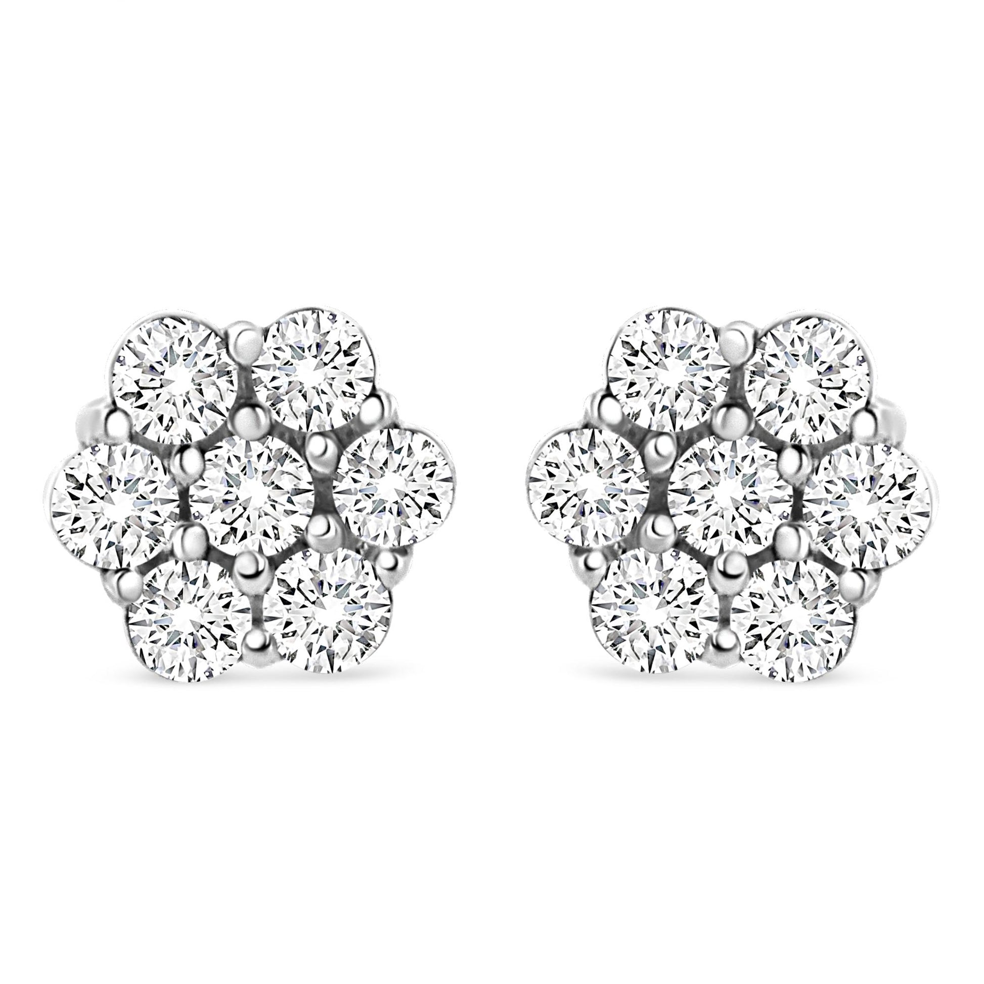 Front view of white metal stud earrings shaped like flowers with round white gemstones in prong settings.