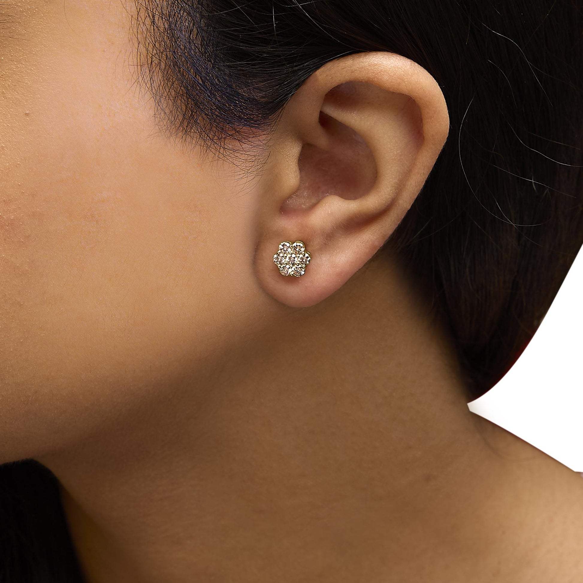 Close-up side view of a model wearing yellow metal earrings with multiple round white gemstones in a clustered prong setting.